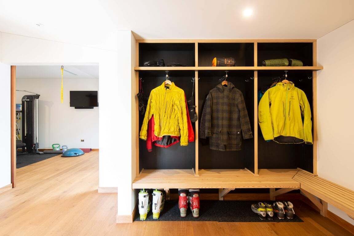 A walk-in closet with multiple shelves and hanging space, a shoe rack, and a television mounted on the wall.