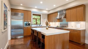 A modern kitchen with wooden cabinets, stainless steel appliances, and a central island. - Luxury 4 BR | AC | Double Garage | Private Hot Tub | Mountain Views | Managed By Aloha Whistler (Whistler)
