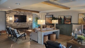 A modern living room with a stone wall, a fireplace, and a flat-screen TV. There are two sofas, a coffee table, and a side table with a lamp. - 3-Bedroom Loft in Park City across from Park City Mountain Resort (Park City)