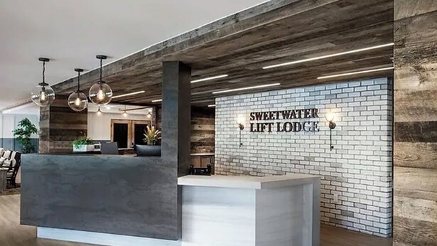 A reception area with a modern design, featuring a reception desk, hanging pendant lights, and a sign that reads "Sweetwater Lift Lodge". - 3-Bedroom Loft in Park City across from Park City Mountain Resort (Park City)