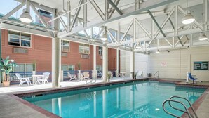 An indoor swimming pool with clear water, surrounded by white lounge chairs and tables, and a high ceiling with visible structural beams. - 3-Bedroom Loft in Park City across from Park City Mountain Resort (Park City)