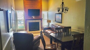 A living room with a fireplace, a television mounted on the wall, a dining table with chairs, and a sofa. - 3-Bedroom Loft in Park City across from Park City Mountain Resort (Park City)