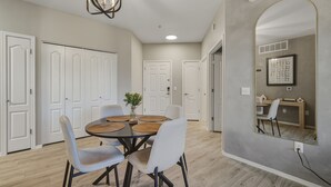 A dining area with a round table, white chairs, and a hanging light fixture. - Modern 2BR/2BA Retreat • Pool • Gym • Free Parking (Phoenix)