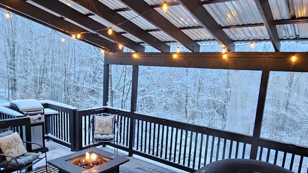 A covered outdoor deck with a fire pit, seating area, and hot tub. - Cozy Winter Cabin • Wood Stove • Mountain View (Chesterville)