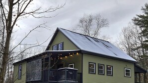 A two-story house with a balcony, a porch, and a snow-covered lawn. - Cozy Winter Cabin • Wood Stove • Mountain View (Chesterville)