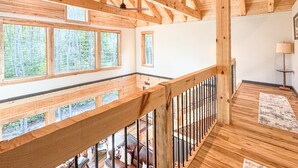 Interior de madera con balcón, ventanas amplias y ventilador de techo.