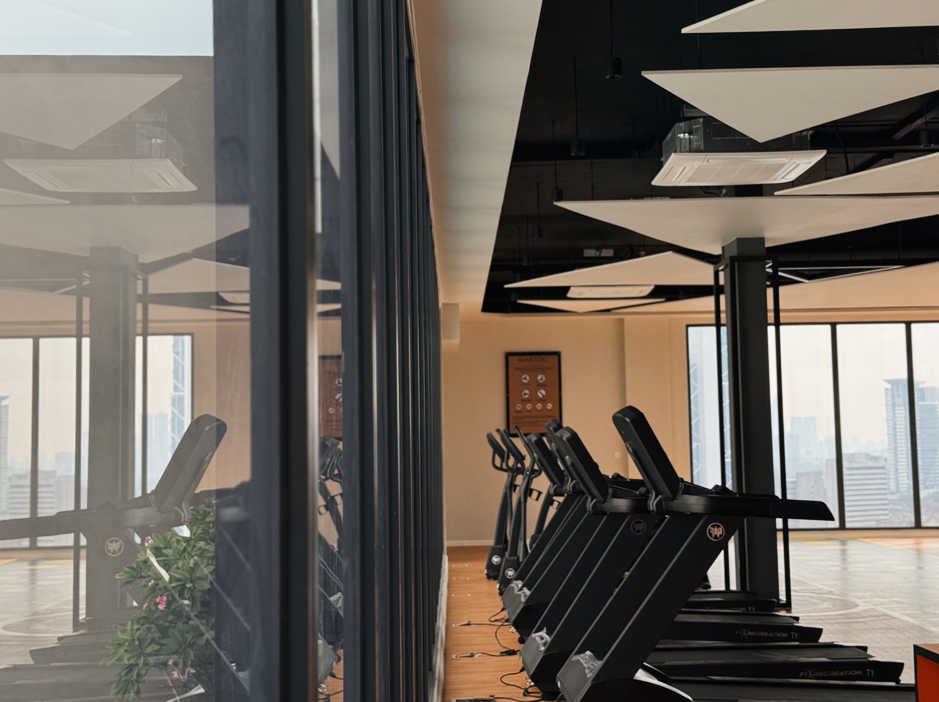 A gym with exercise equipment and large windows offering city views.