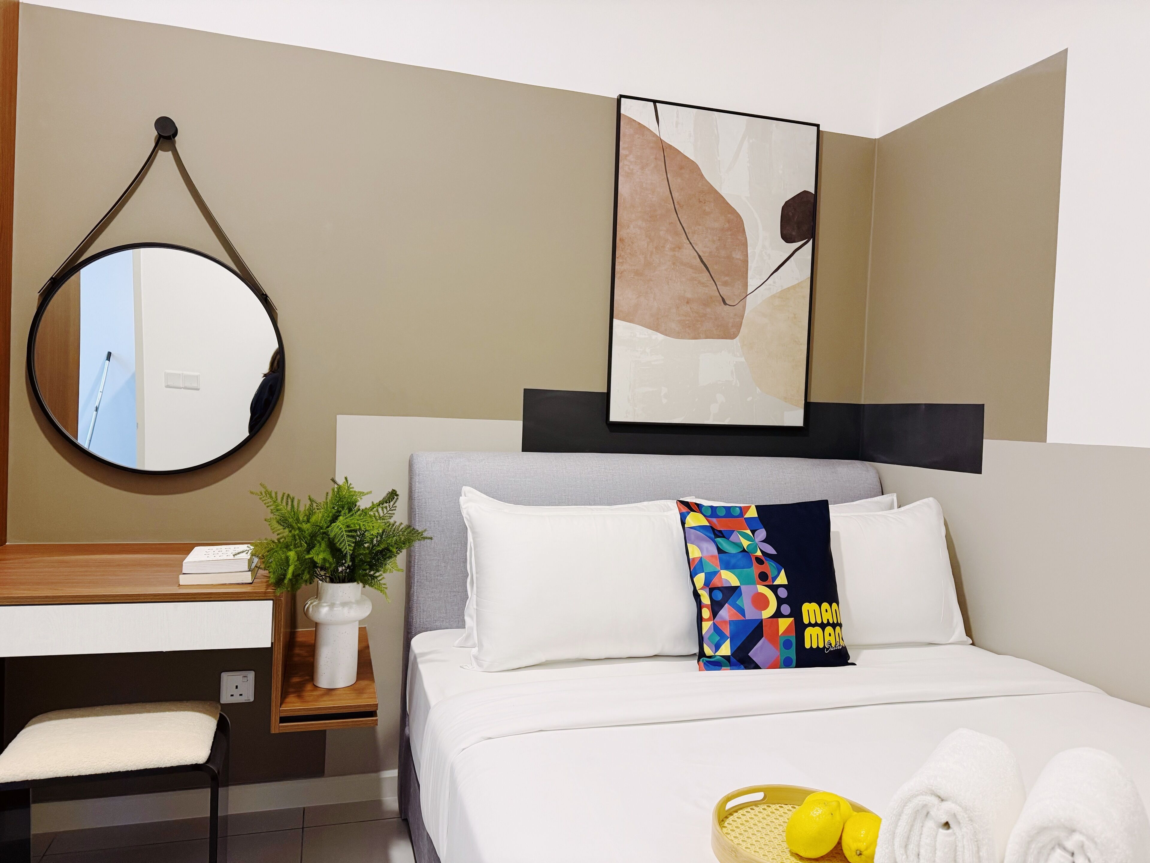 A hotel room with a bed, a desk, a mirror, and a wall-mounted artwork.