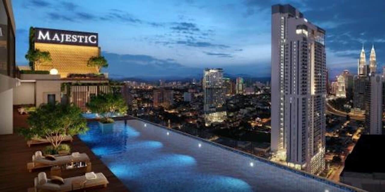 A rooftop pool with a cityscape view, a sign reading "MAJESTIC," and high-rise buildings in the background.