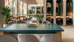 Un'area lounge moderna con un tavolo lungo, sedute confortevoli e piante in vaso.