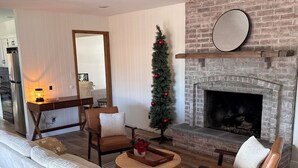 Ein Wohnzimmer mit Kamin, Tannenbaum und einer gemütlichen Sitzecke.