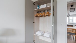 Ein begehbarer Kleiderschrank mit Holzböden, hängenden Holzkleiderbügeln und ordentlich gefalteten weißen Handtüchern.