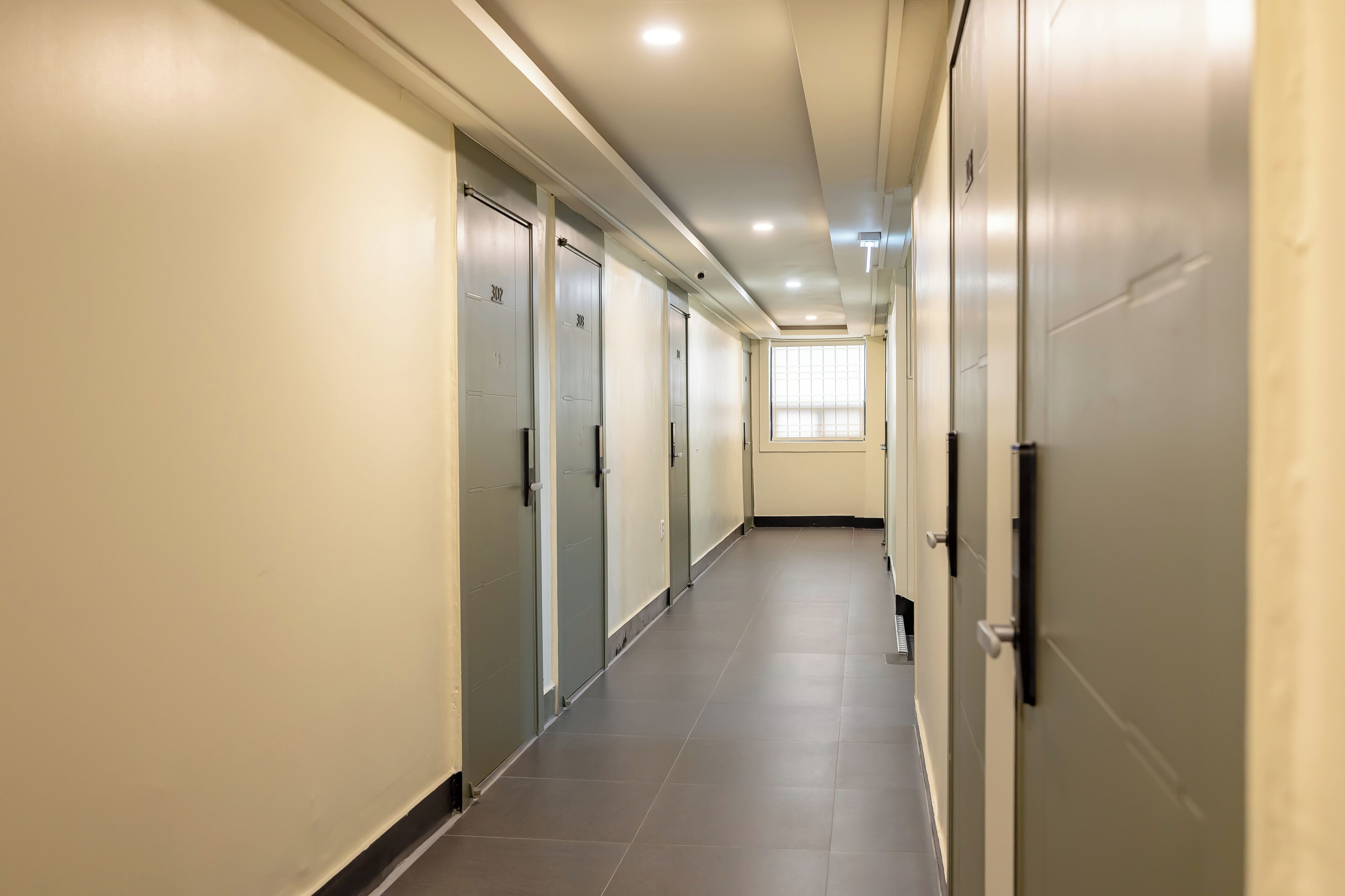 A long, narrow hallway with doors on both sides, leading to individual rooms.