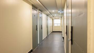 A long, narrow hallway with doors on both sides, leading to individual rooms.