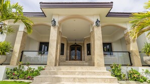 A grand entrance with a set of marble steps leading to a covered porch supported by columns. - Stunning Luxury Pool OasisRooftop W/ Ocean Views (Noord)