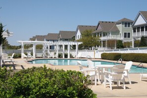 A pool area with white deck chairs and a covered seating area. - Carolina Comfort: New Rental, Private Pool, Community Amenities (Corolla)