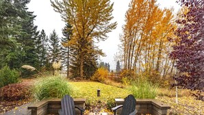 A patio with two Adirondack chairs facing a garden with a variety of trees and plants. - Slope View - Parkdale Perfection, Views For Miles, Gorgeous! (Mount Hood Parkdale)