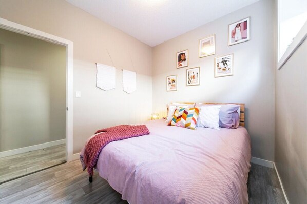 A bedroom with a bed, a door, and wall-mounted pictures.