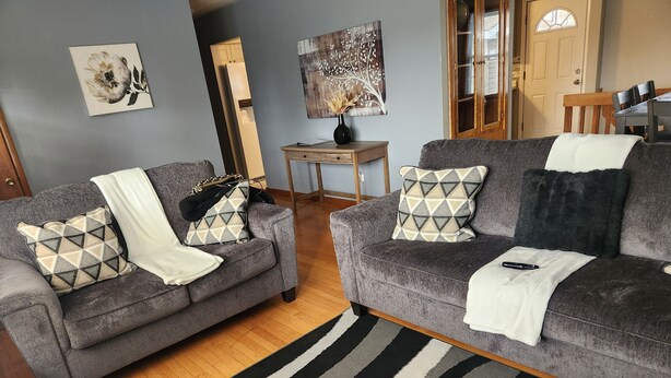 A living room with two grey sofas, patterned throw pillows, a black and white striped rug, and a wooden coffee table. - The Cozy Retreat 1.7 miles from the Naval base (North Chicago)