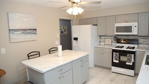 A kitchen with grey cabinets, a white refrigerator, a microwave, a stove, and a ceiling fan. - The Cozy Retreat 1.7 miles from the Naval base (North Chicago)