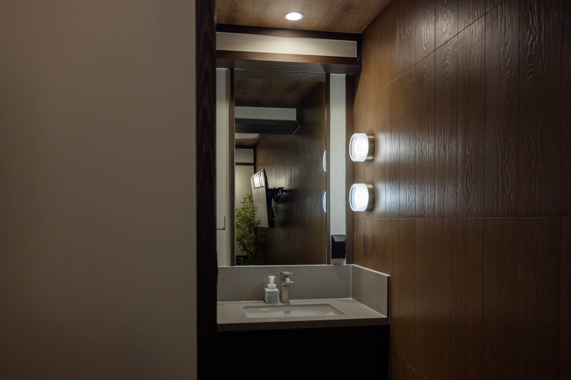 A bathroom with a large mirror, a sink, and two wall-mounted lights.