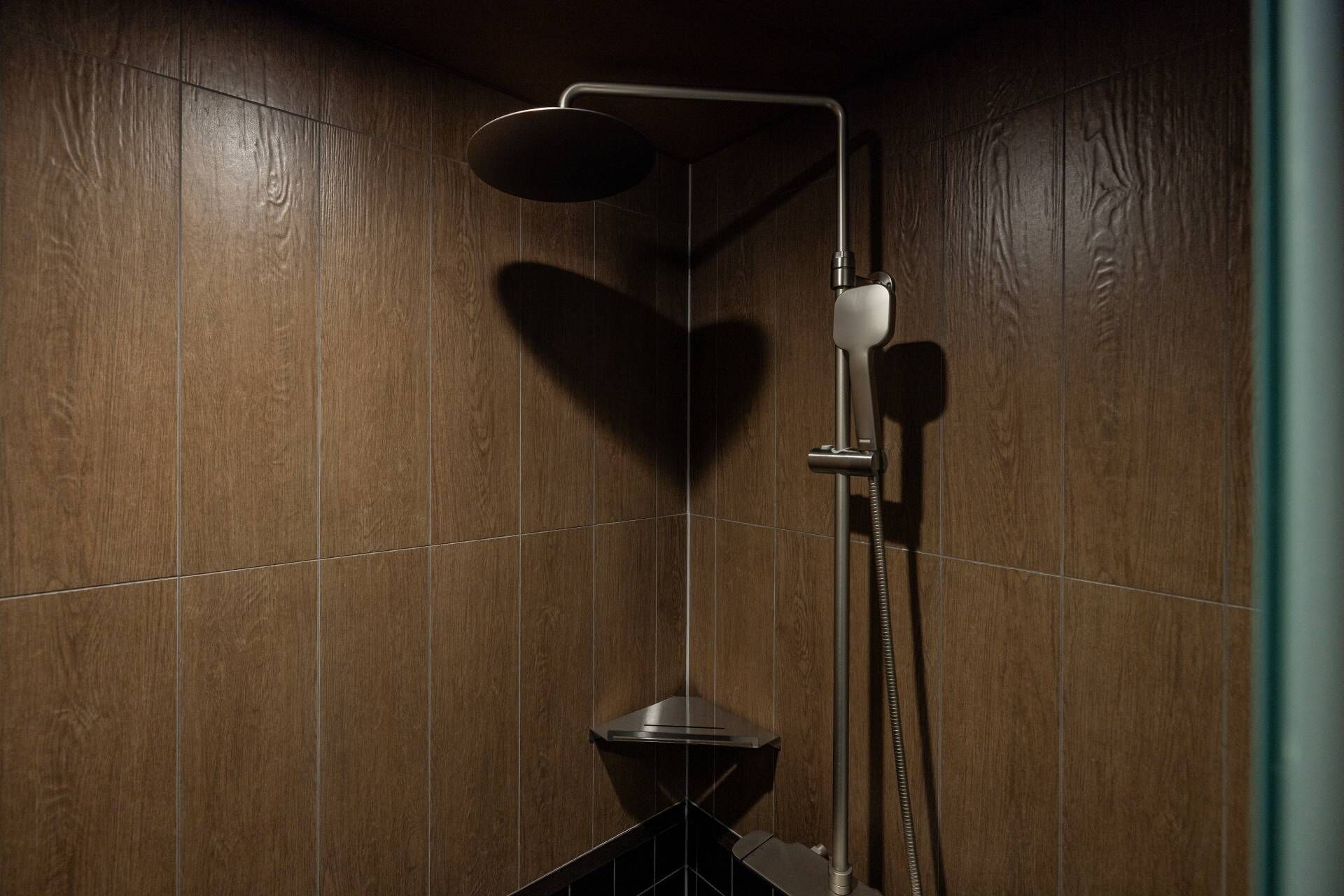 A shower with a handheld showerhead and a wall-mounted faucet.