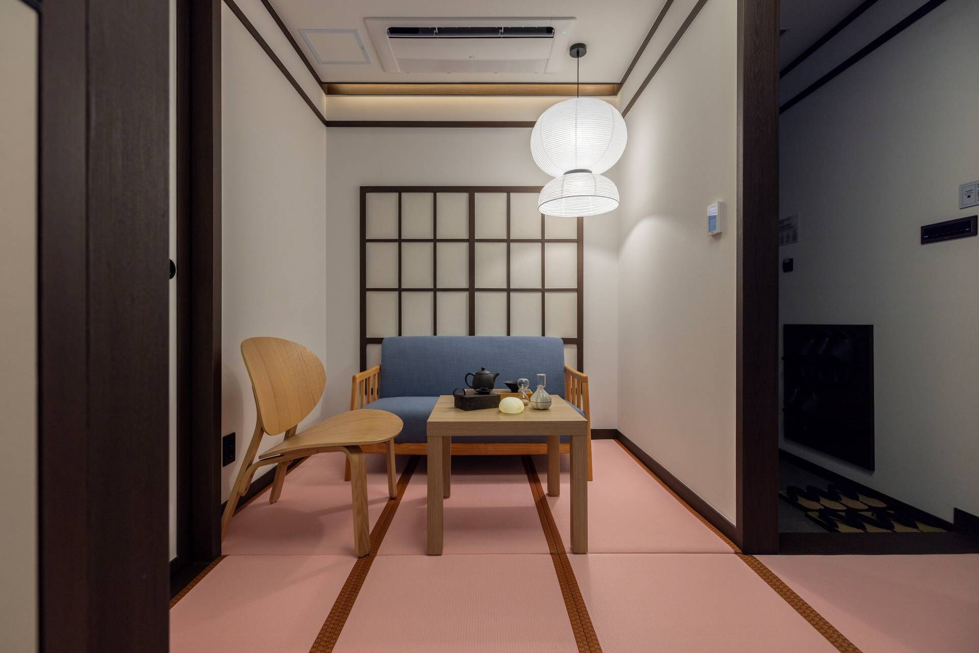 Ein traditioneller japanischer Raum mit Tatami-Bodenbelag, einem niedrigen Tisch mit Teeservice und einem blauen Sofa.