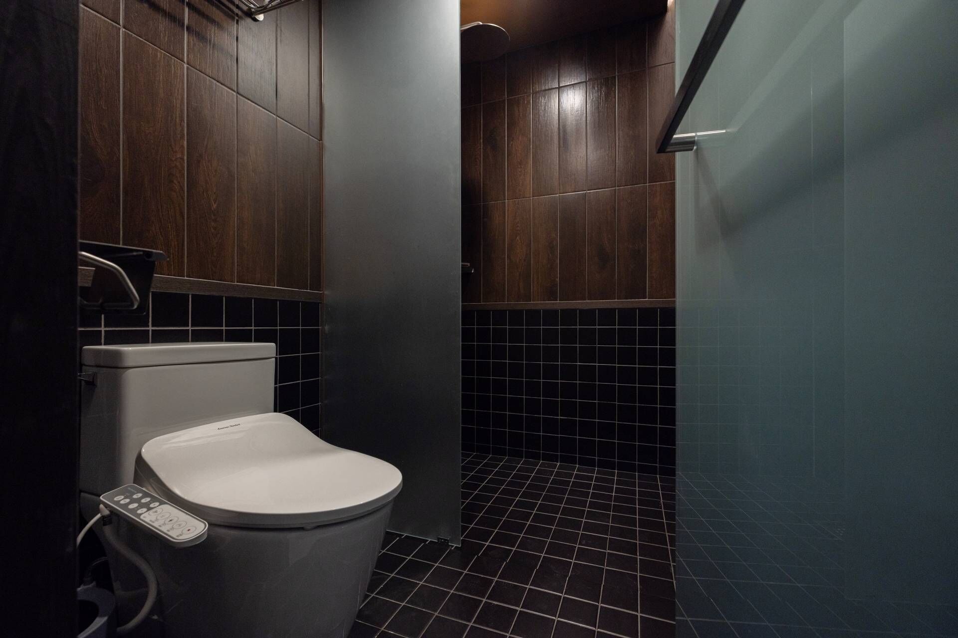 A modern bathroom with a toilet, a hand dryer, and a shower area.