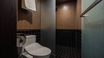 A modern bathroom with a toilet, a hand dryer, and a control panel.