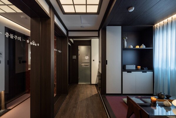 A modern hotel lobby with a wooden floor, a reception desk, and a seating area with a table and chairs.