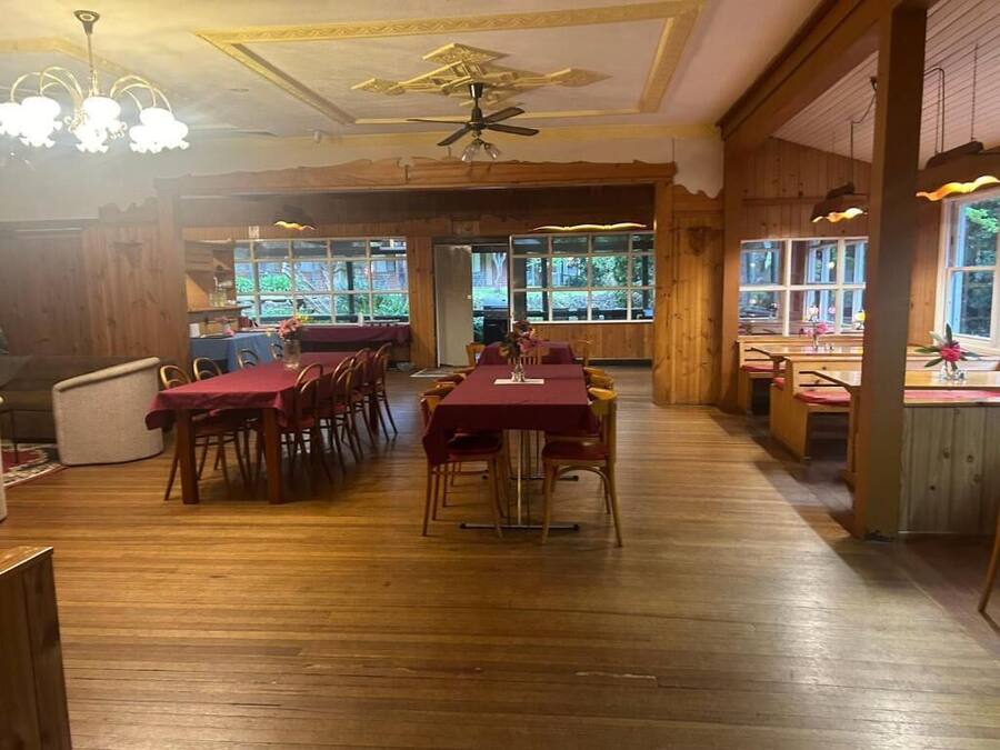 A restaurant with wooden floors and tables, large windows, and a ceiling fan.