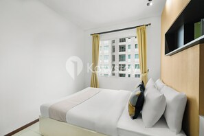 A modern hotel room with a bed, a window with yellow curtains, and a view of a building. - Javen by Kozystay - Thamrin (Jakarta)