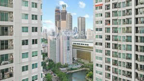 A high-rise residential building with multiple balconies, a river in the foreground, and other high-rise buildings in the background. - Javen by Kozystay - Thamrin (Jakarta)