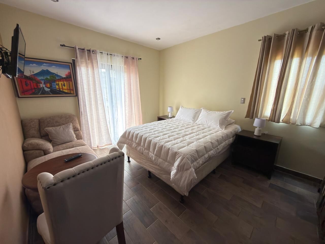 A bedroom with a bed, a chair, a nightstand, and a painting on the wall.