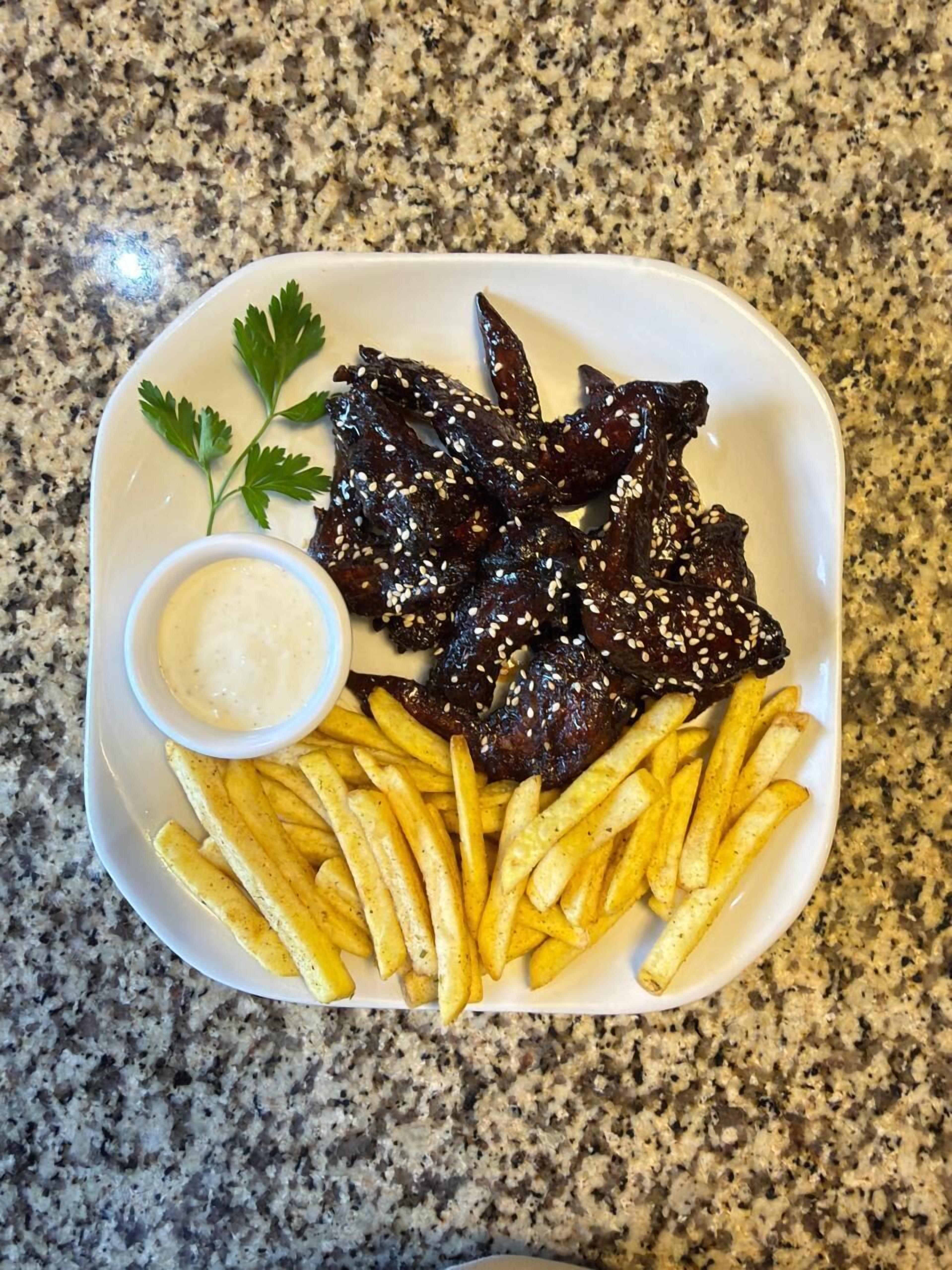 Un piatto di cibo con patatine fritte e una piccola ciotola di salsa.