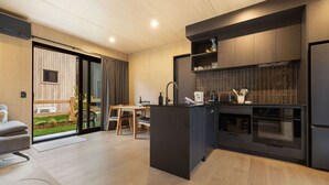 A modern kitchen with dark cabinetry, a built-in oven, and a dining area with a table and chairs.
