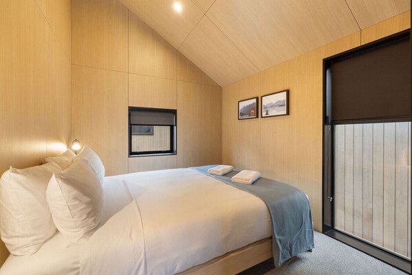 A bedroom with a bed, a window, and a door.