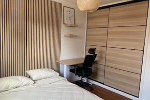 A bedroom with a bed, a desk, and a wardrobe.