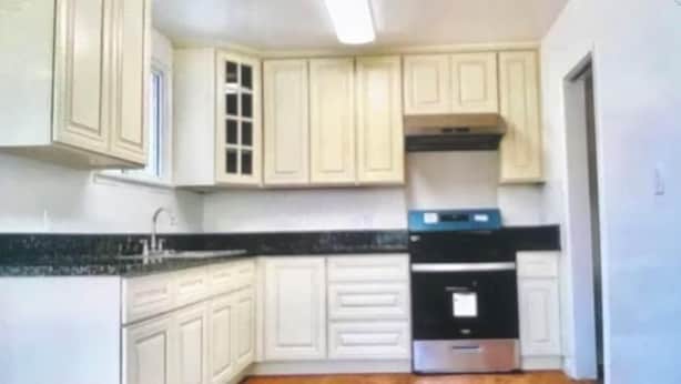 A kitchen with white cabinets, a black countertop, and a stainless steel oven. - SUNNY HOME (Alhambra)