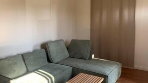 A corner of a room with a grey sectional sofa and a small wooden coffee table. - SUNNY HOME (Alhambra)