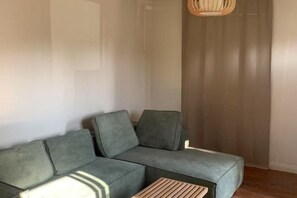 A modern living room with a grey sectional sofa, a wooden coffee table, and a woven light fixture. - SUNNY HOME (Alhambra)