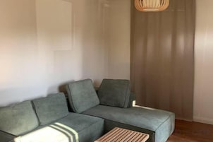 A modern living room with a grey sectional sofa, a wooden coffee table, and a woven light fixture.