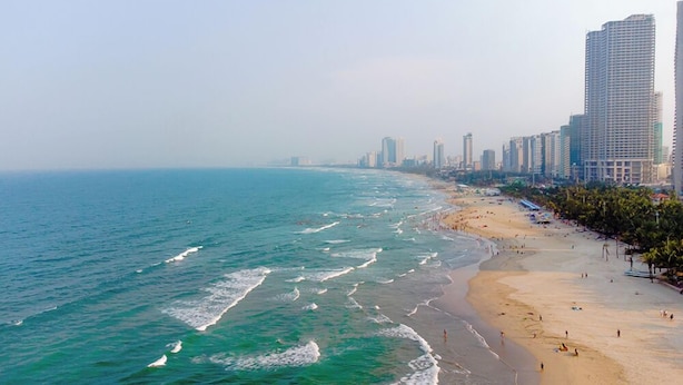 A coastal cityscape with a sandy beach and high-rise buildings along the shore.