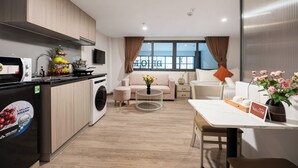 A modern kitchen with a washing machine, a dining area with a table and chairs, a sofa, and a view of the city.