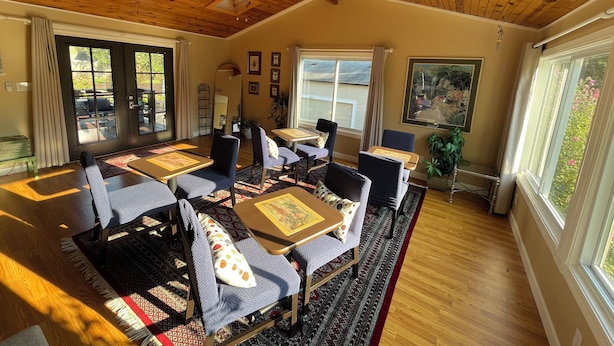 A dining area with wooden ceiling beams, a ceiling fan, and large windows with curtains. -  Beautiful  home with 4 community areas and 5 bedrooms. (Indianapolis)