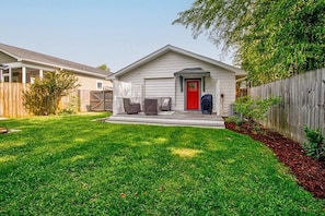A single-story house with a red door, a covered porch, and a fenced yard.