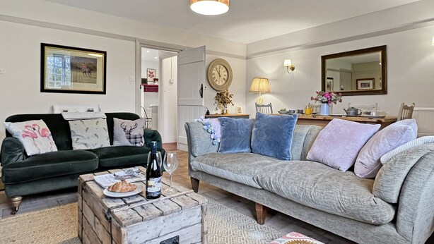 Een woonkamer met twee banken, een houten kist en een eethoek met een tafel en stoelen.