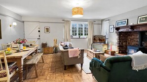Een gezellige woonkamer met een open haard, een eethoek met een houten tafel en een groene bank.