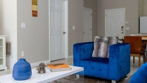 Una sala de estar con un sofá azul, una mesa de centro blanca y un libro.