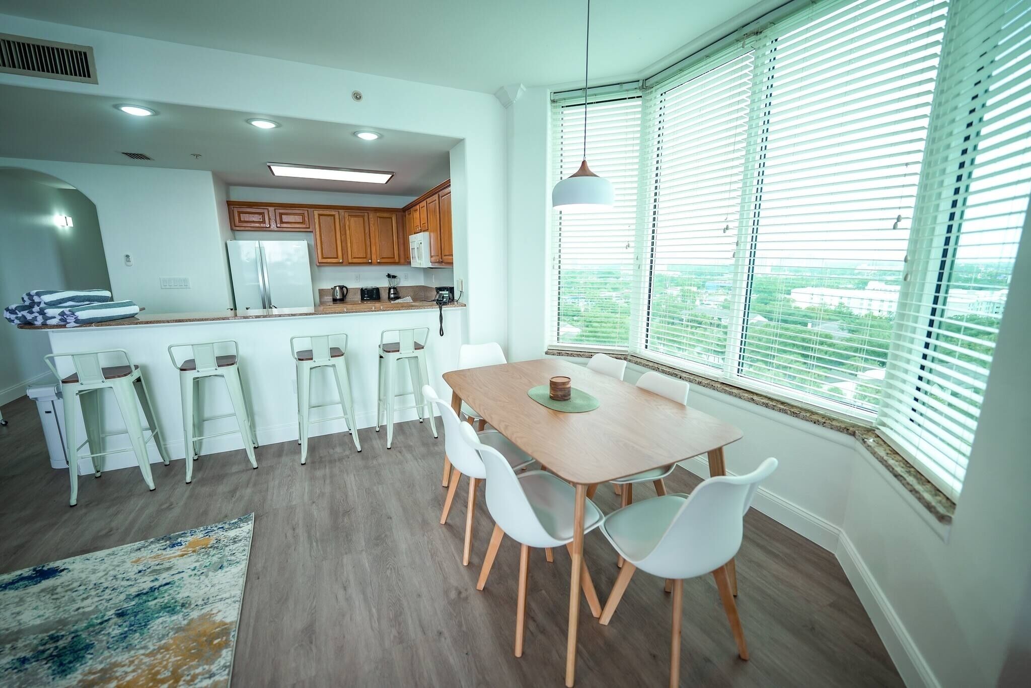 Een moderne keuken met houten kastjes, een koelkast en een eethoek met een tafel en stoelen.